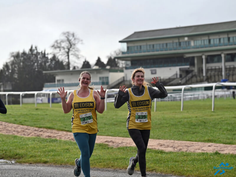 Two women running with their hands in the air.