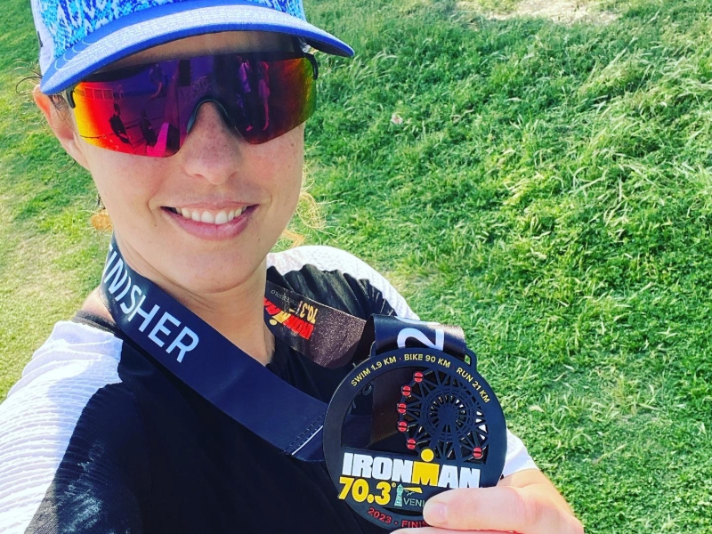 Woman smiling holding Venice Ironman medal