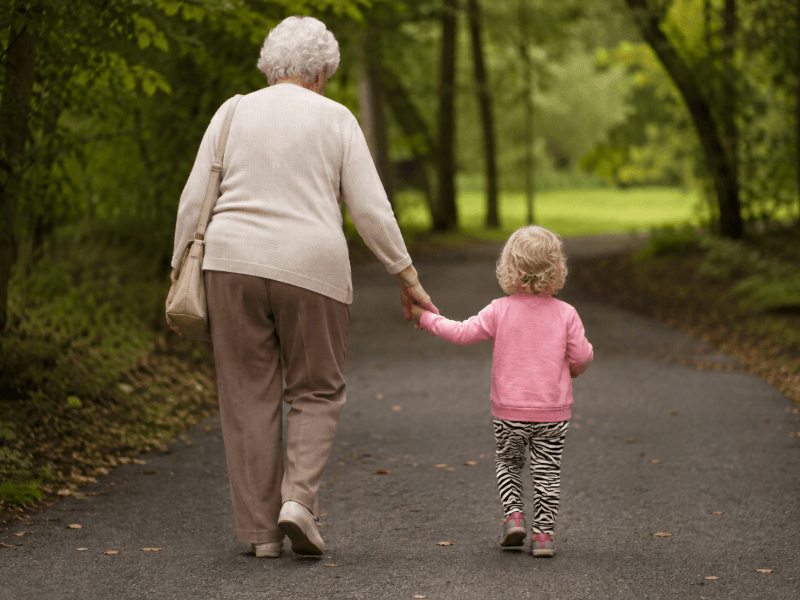 Older lady and young child walking away, holding hands